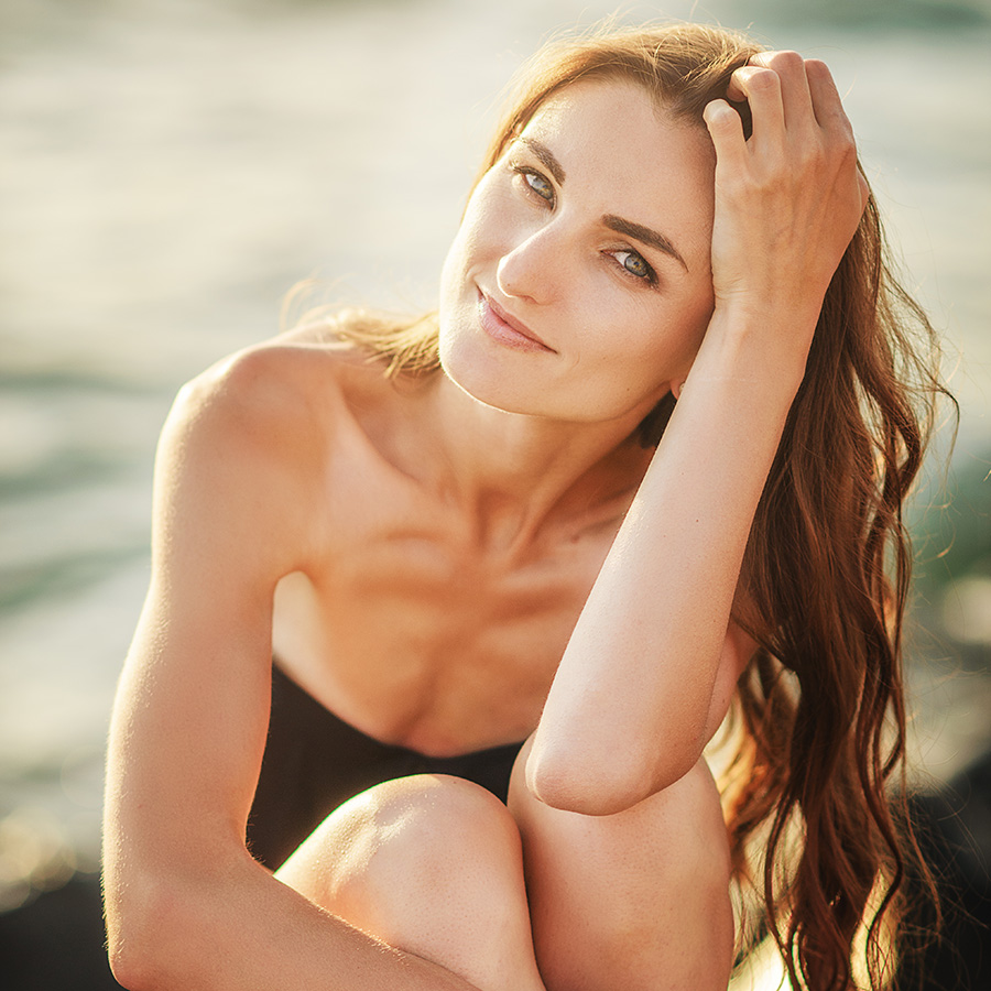 Blonde haired woman sitting by a lake